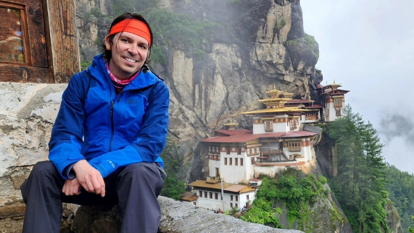       Person posing in front of a traditional Bhutanese monastery.
  