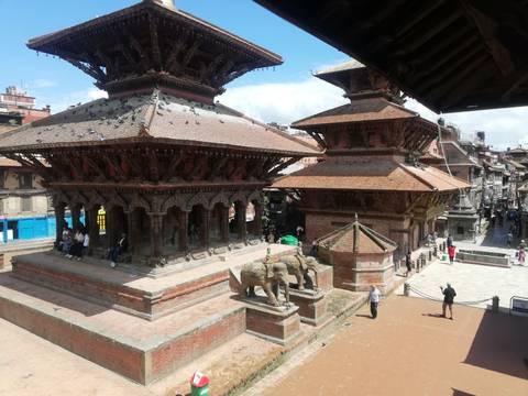       Temple structures with tourists and statues in Kathmandu.
  