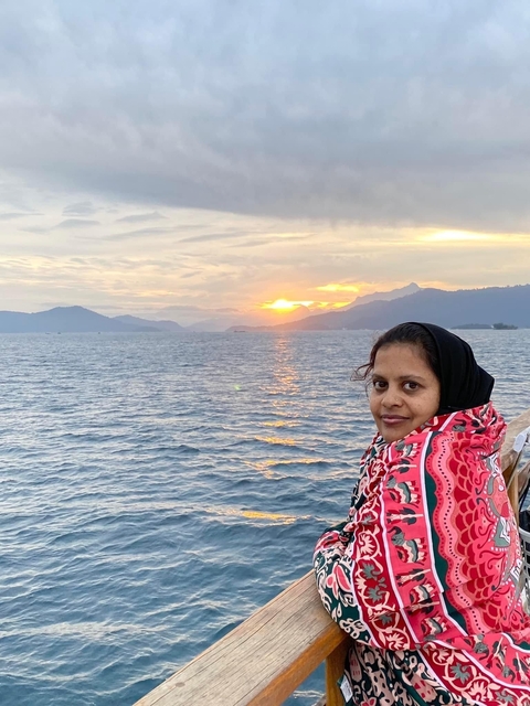       A person on a boat, enjoying the sunset view over the water.
  