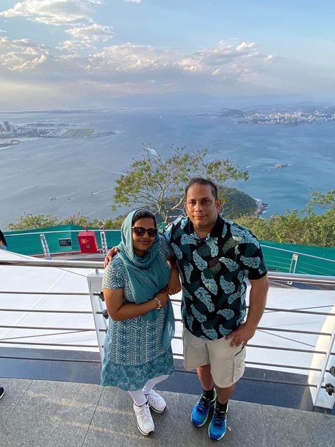 A couple posing with a scenic view of the coastline.