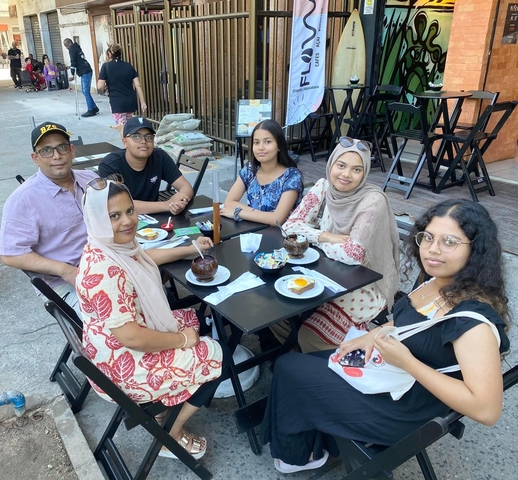 A family sitting at an outdoor cafe with desserts on the table.
