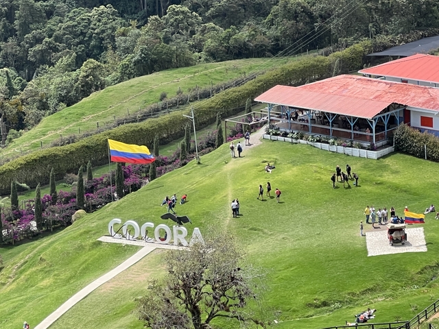 View of a park with a large Colombian flag and 'Cocora' sign.
