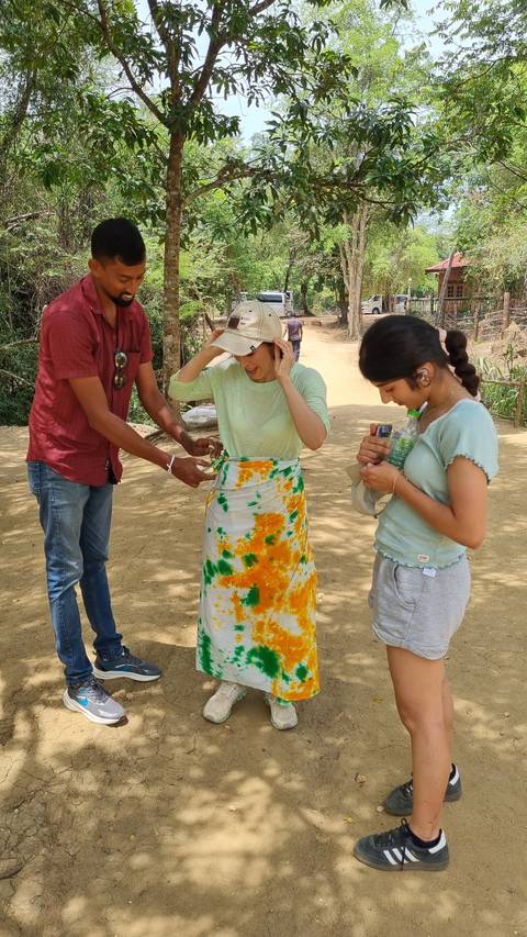 Three people examining a small object outside.