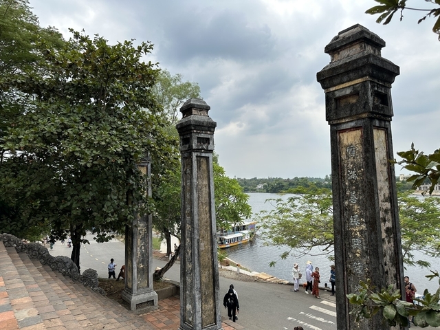 Located near a body of water with historic stone pillars and trees.