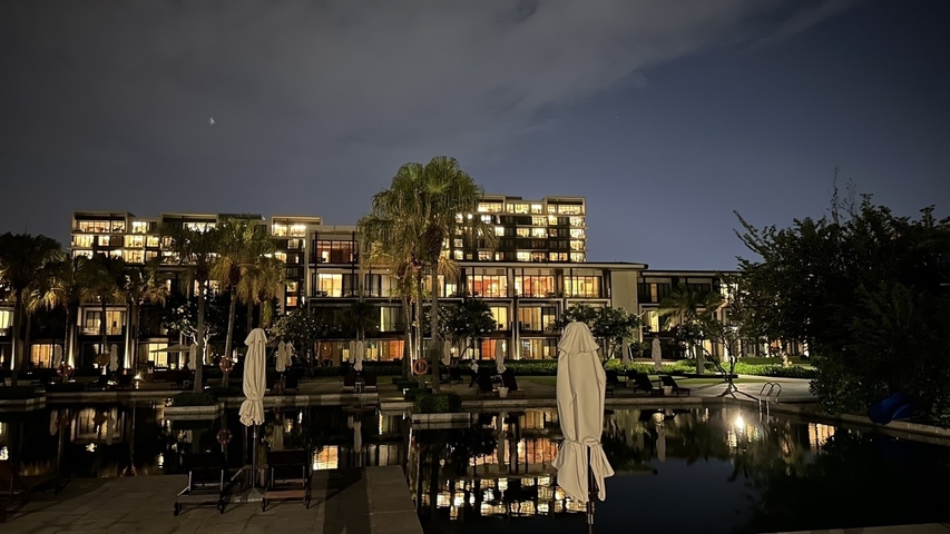 Night view of a well-lit building with a reflection on water.