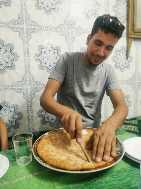       A man preparing food indoors with a patterned wall in the background
  
