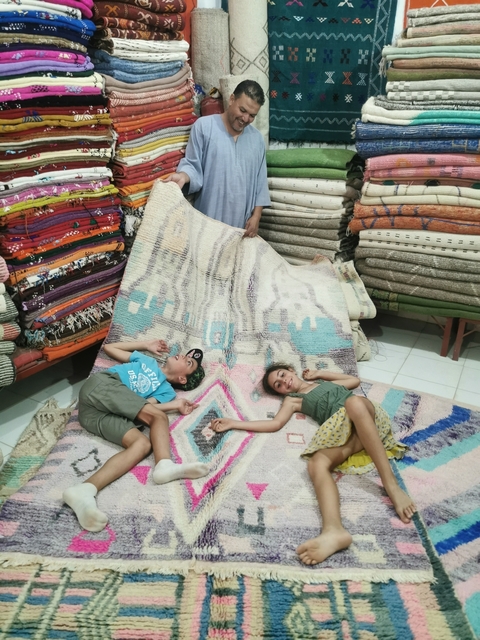       Two children lying on large display rugs in a store
  