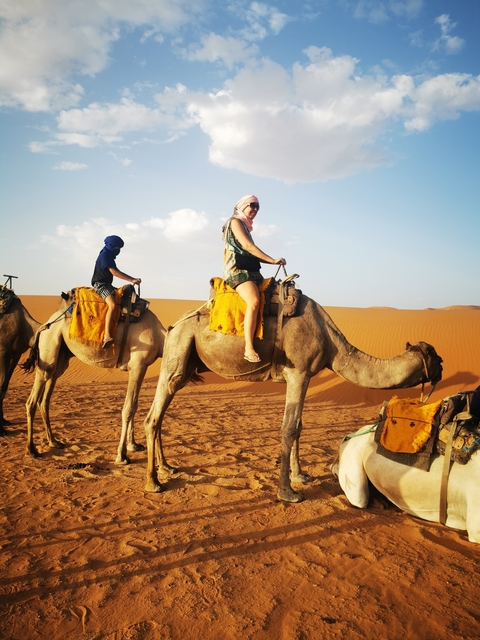       People riding camels in the vast desert
  