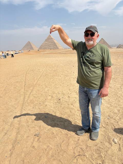 Man posing with the pyramids in the background.