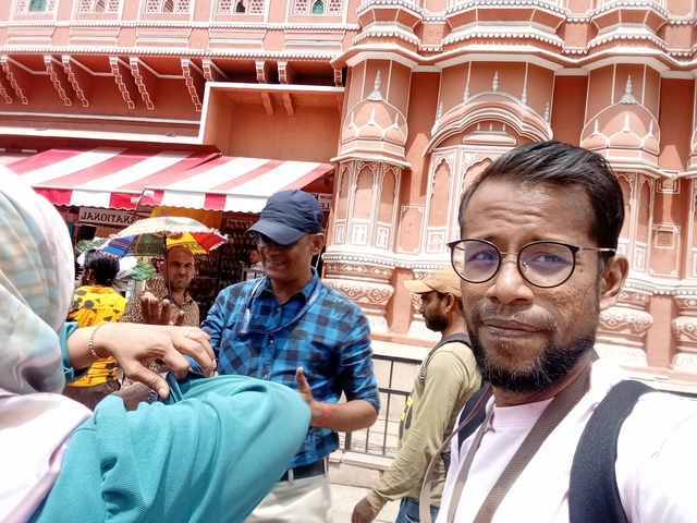 People taking a selfie with pink architecture in the background.