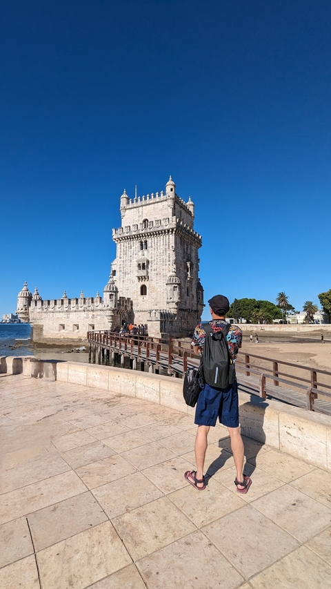 Person in front of the Belem Tower on a sunny day.