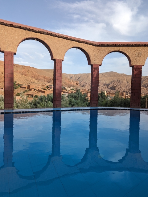       Swimming pool overlooking a valley with mountains.
  