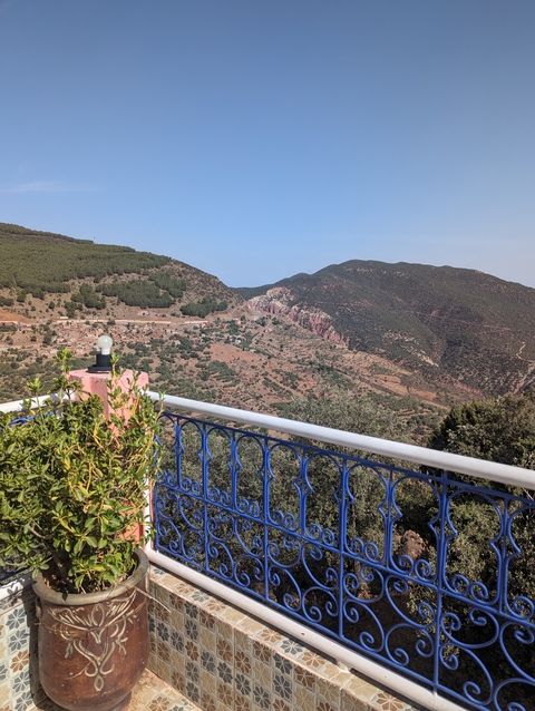       View of a hilly landscape with a small village and mountains in the distance.
  