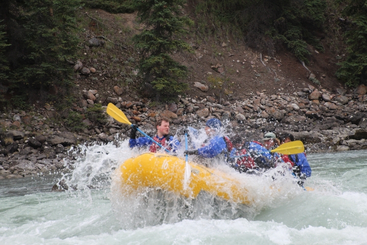 Group white water rafting on a river surrounded by rocky landscape.