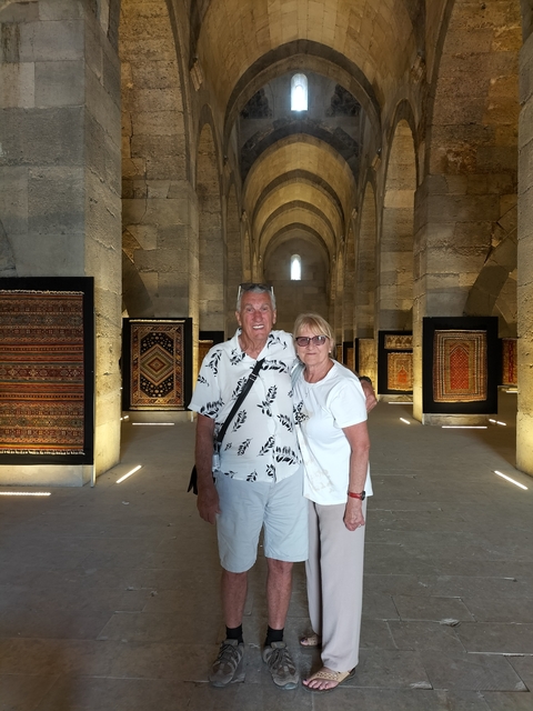 Couple posing in front of a historic building displaying carpets.
