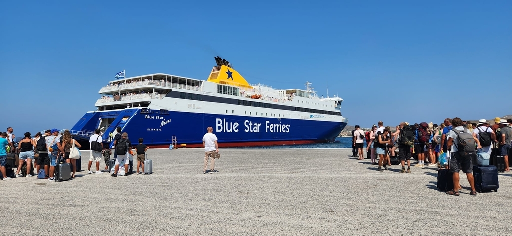 People boarding a Blue Star Ferry with clear skies.