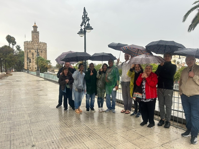Group of people with umbrellas in front of a historic tower.