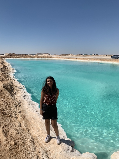 Person standing near a turquoise lake.