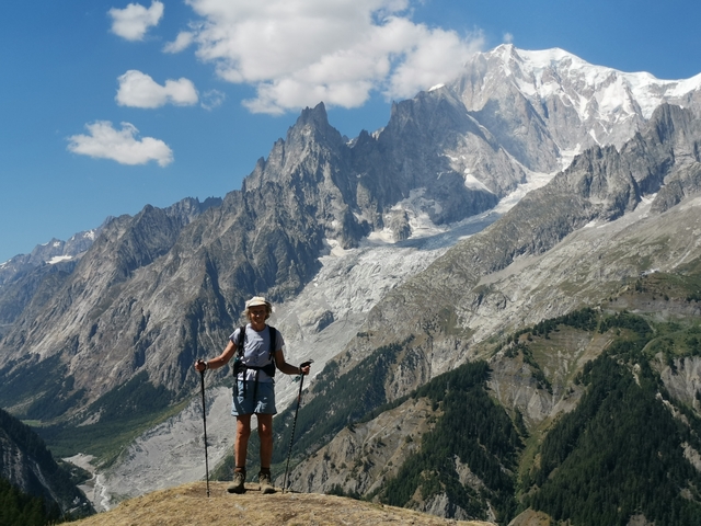 Hiker with trekking poles in a mountainous landscape.