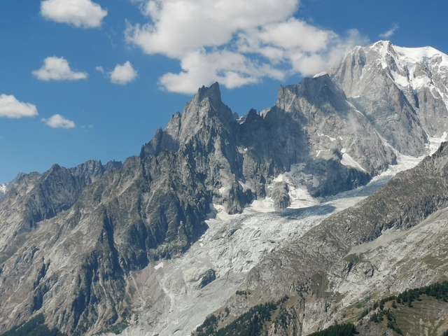 Mountain range with glaciers under a blue sky.