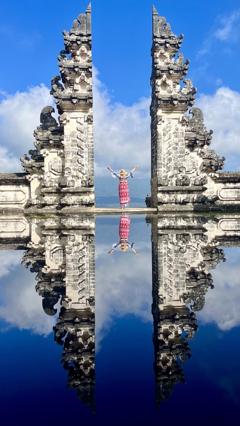 Person posing between intricately carved stone gates