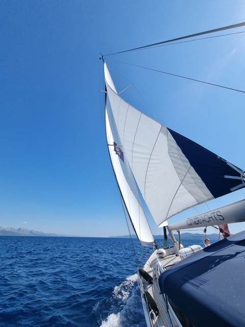 Close-up of a sailing yacht's sail against a clear blue sky.
