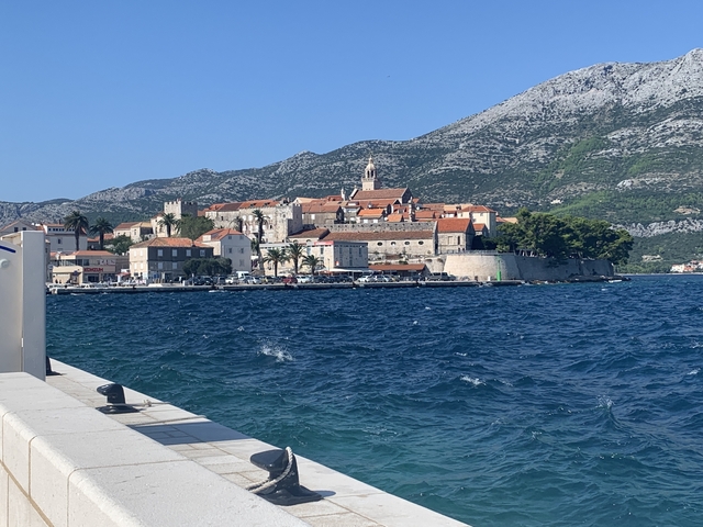 View of a coastline with historic buildings and mountains.