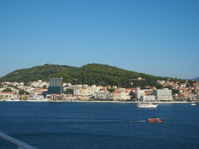       Coastal town with modern buildings and hills in the background.
  