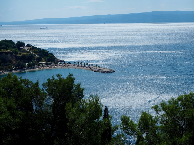       Sparkling seascape with a small beach and trees.
  