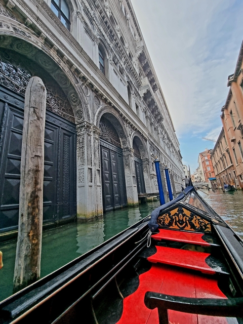       Gondola view of Venice canal with ornate building facades.
  