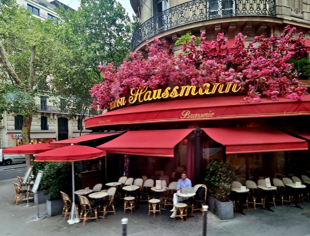 Cafe Haussmann with red awnings and flower decorations.