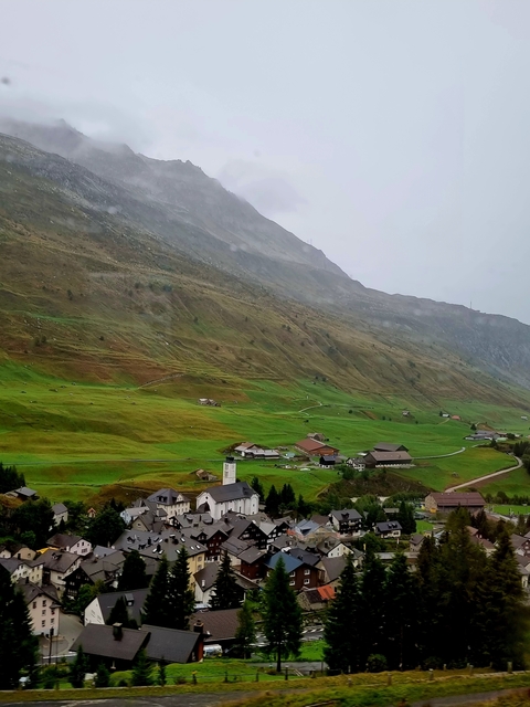 A lush green valley with scattered houses.