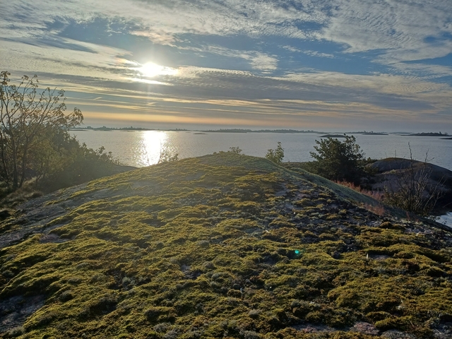 Sunset view over the sea with rocky hills.