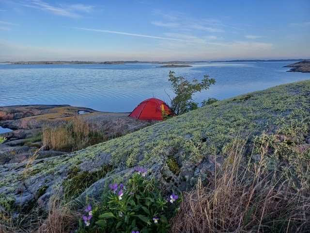 Rocky coastal landscape with a red tent.
