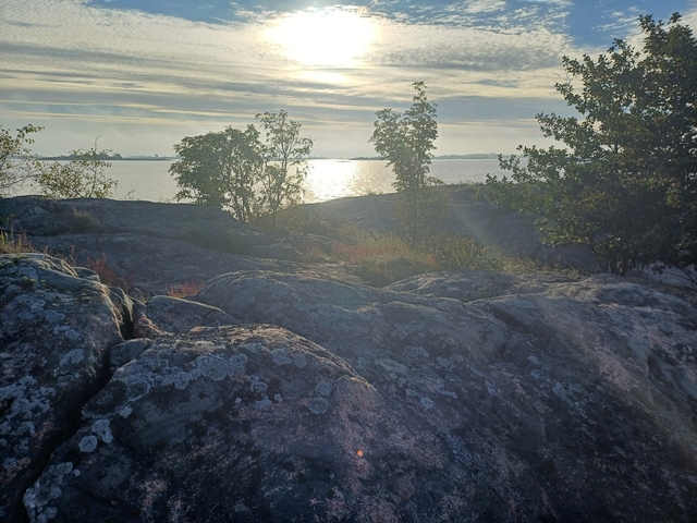 Coastal view with sun reflecting on water.