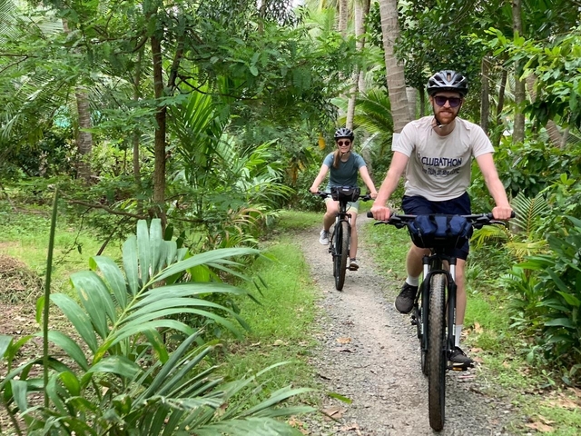 Cyclists riding through a lush green path.