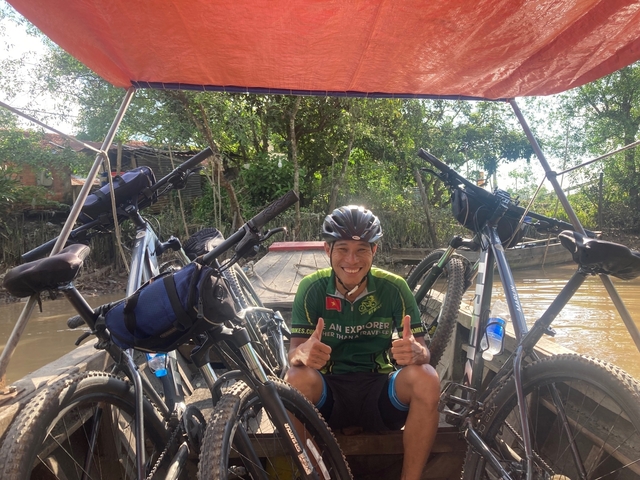 Smiling cyclist giving thumbs up on a boat.