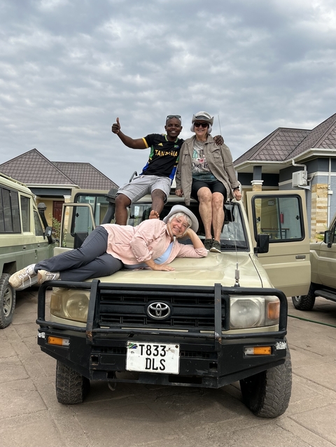       Three people posing on a safari vehicle.
  