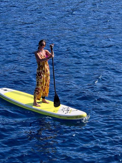 Person paddleboarding on clear blue water.