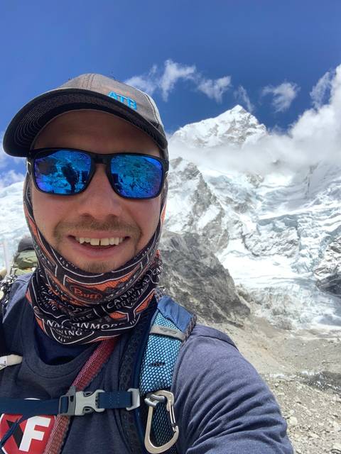 A man in sunglasses with snowy mountains in the background.
