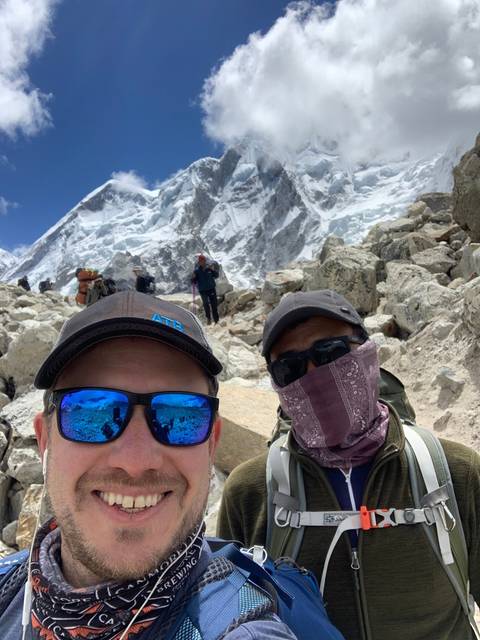 Two climbers smiling in front of snowy peaks.