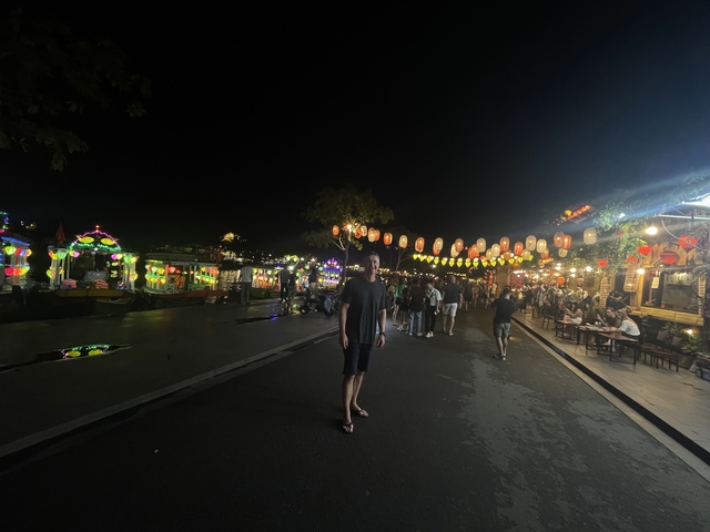 Person walking on a brightly lit street at night.