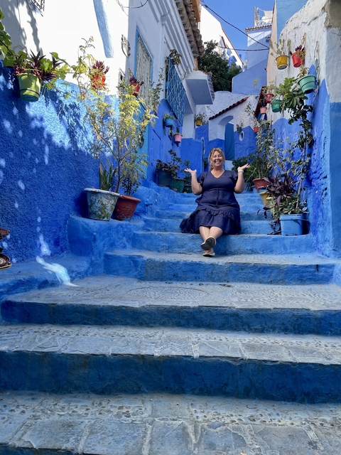 Person sitting on blue-painted stairs surrounded by pots.
