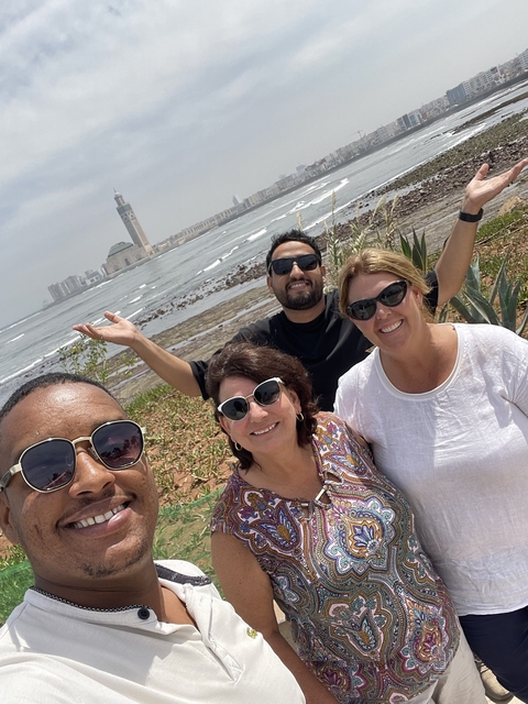 Group photo at a coastal location with a mosque in the background.