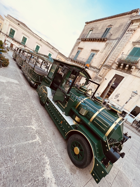       Decorative touristic train parked on a street.
  