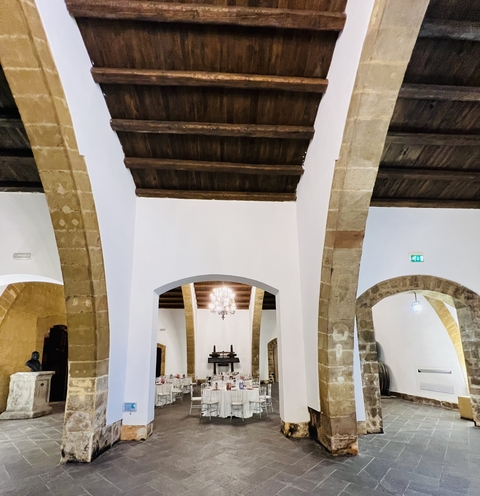Interior of a wine cellar with arches and stone walls.