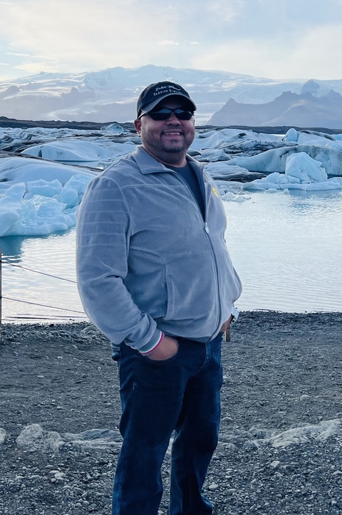       Person in a jacket standing near a lake with icebergs.
  