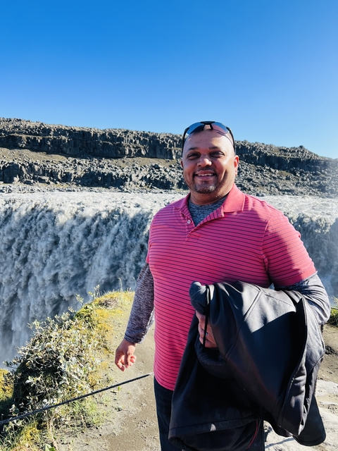       Man standing in front of a waterfall.
  