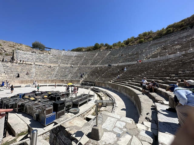       Ancient amphitheater with people exploring.
  