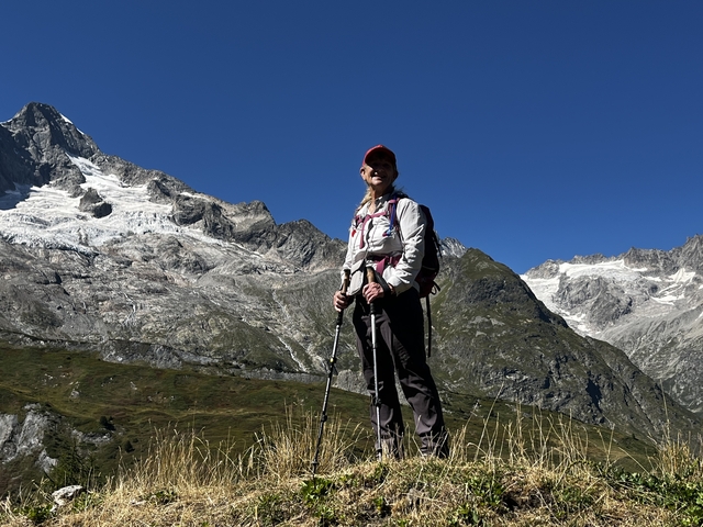 Hiker standing on a grassy slope with mountain views.